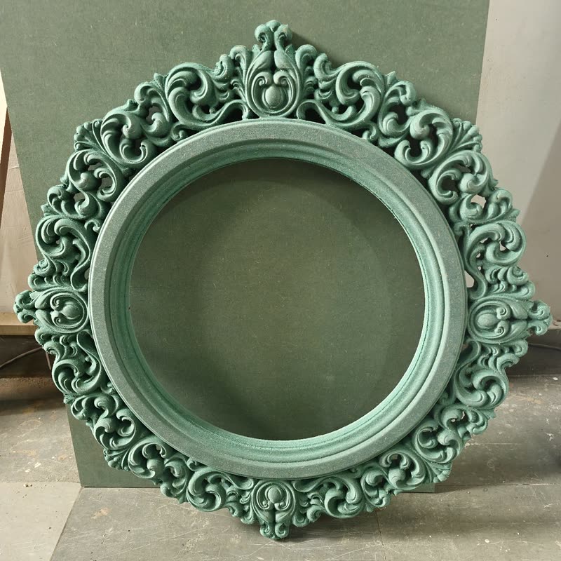 CNC carved mirror frame with scrollwork relief around a turned opening, primed MDF