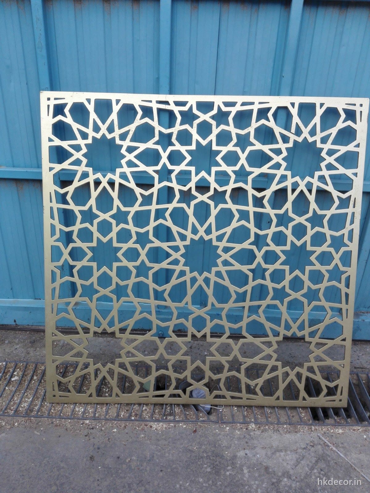 CNC cut jaali screen with an interlocking geometric star pattern fixed in place with daylight behind it