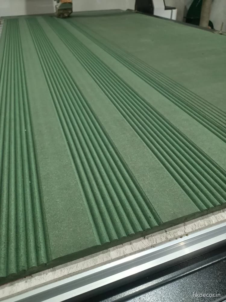 Close up of a CNC router cutting parallel ribs across a primed board on the bed