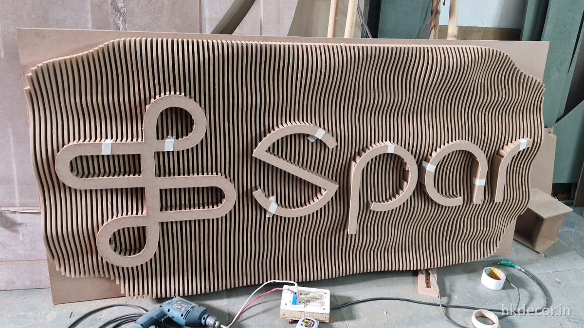 CNC cut parametric signage with the Spar logo and wordmark raised out of a wave-cut rib field, Dream3 Bijwasan